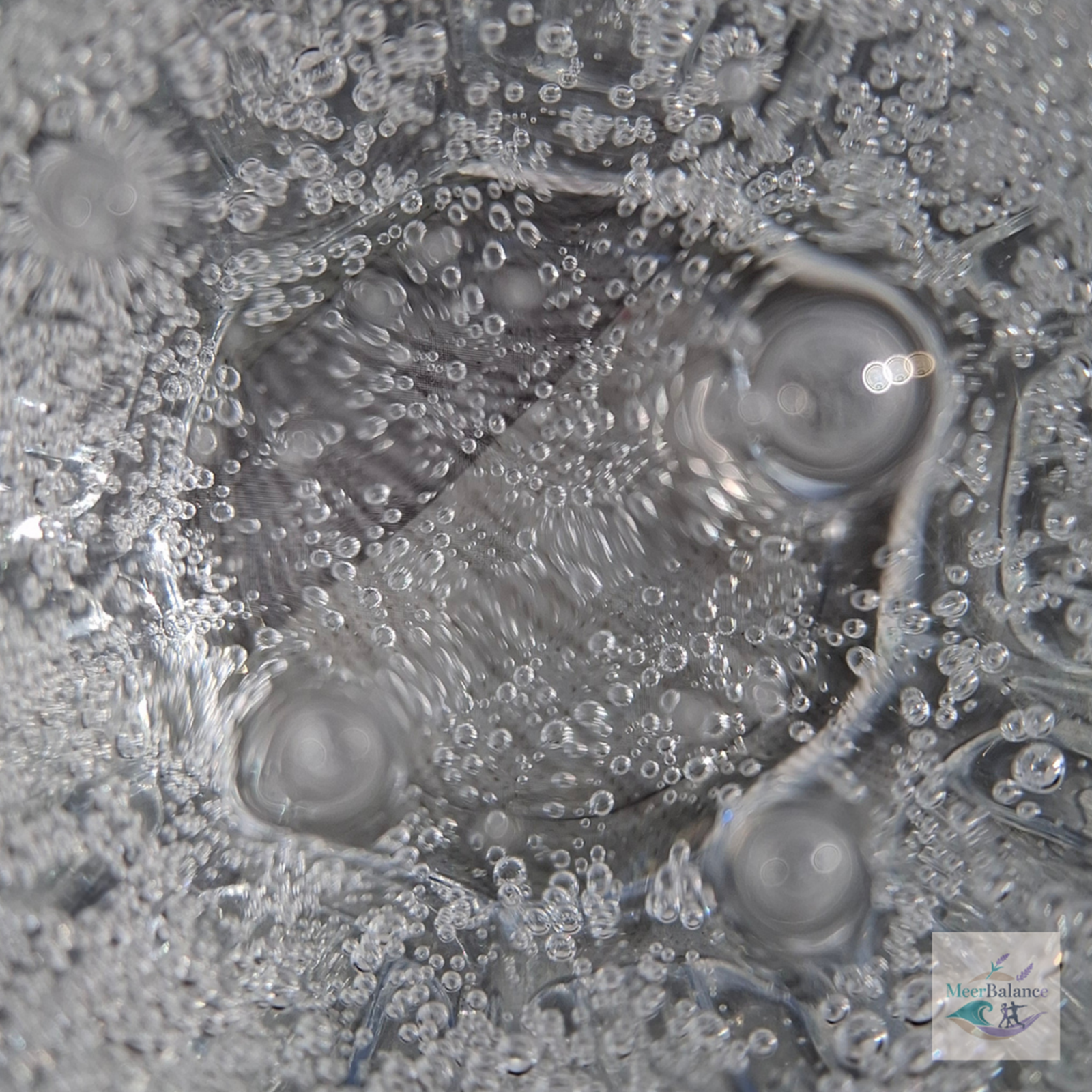 Blick von oben in ein Glas Sprudelwasser mit feinen Kohlensäurenbläschen als Symbol für bewusste Selbstfürsorge und Achtsamkeit