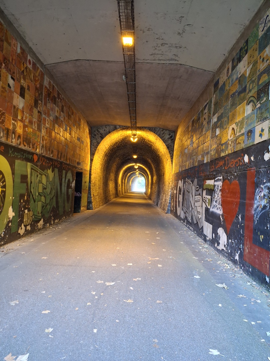Beleuchteter Tunnel der Korkenziehertrasse in Solingen mit Graffiti an den Wänden