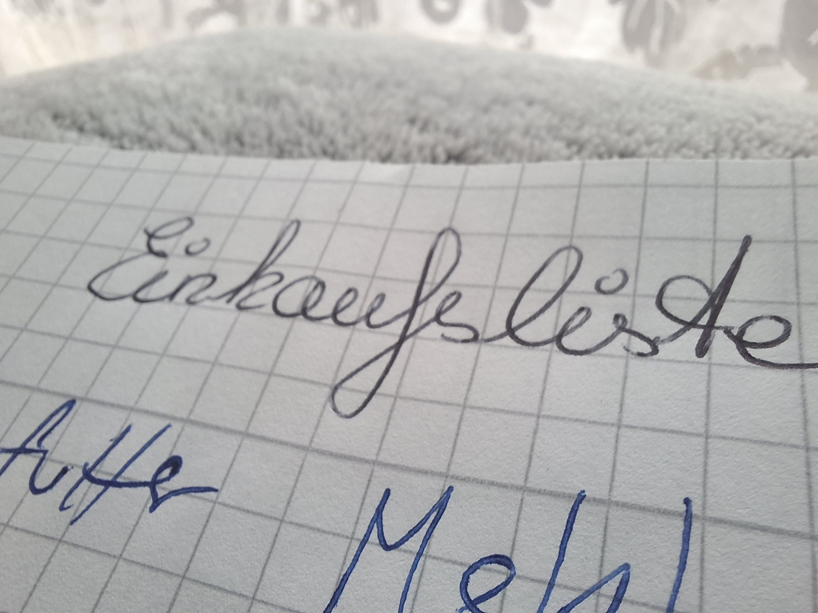 Handgeschriebene Einkaufsliste auf kariertem Papier